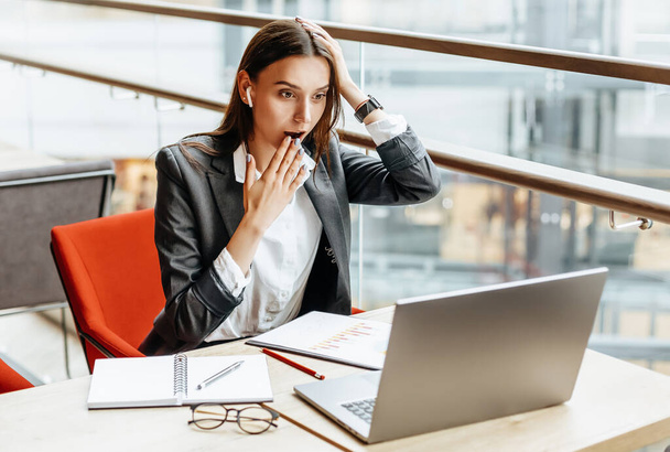 Girl works on a laptop in the workplace. Businesswoman is shocked by the crisis. Successful woman creates a startup and makes decisions. - 写真・画像