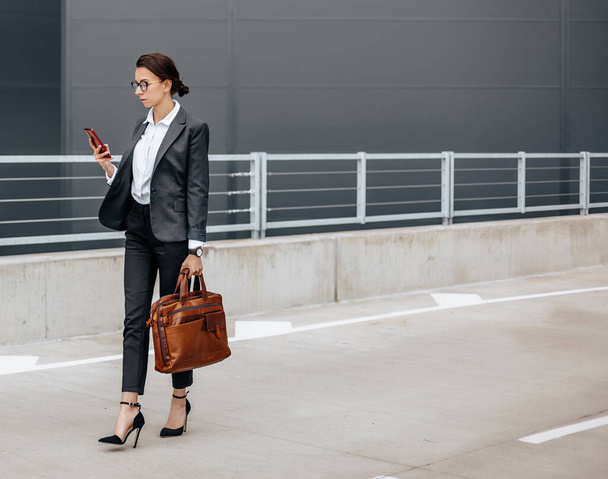 A business woman checks the time in the city during a working day waiting for a meeting. Discipline and timing. An employee goes towards a corporate meeting. - Foto, afbeelding