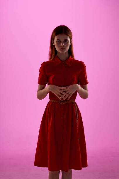 hermosa mujer en vestido rojo gestos de mano de lujo fondo rosa - Foto, imagen