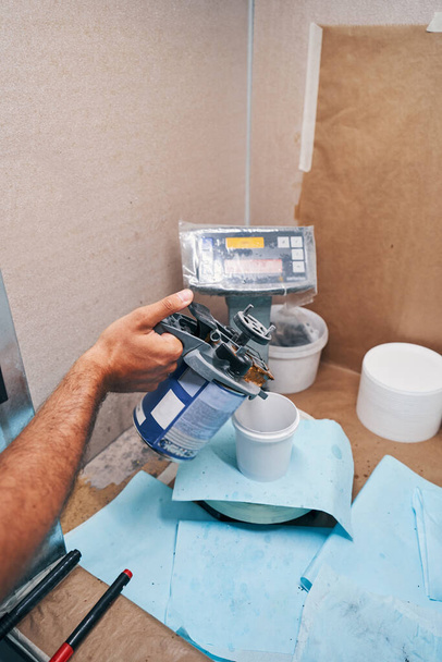Worker adding paint to small bucket on scales - Valokuva, kuva