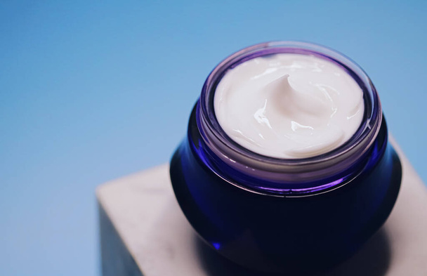 Cuidado de la piel antienvejecimiento y cosméticos, crema facial de belleza en frasco sobre fondo azul - Foto, Imagen