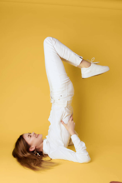 woman standing on her back with her legs raised upside down gold background - Foto, Imagem