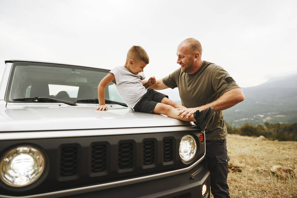Dad and son playing on the hood of a car on road trip - Fotografie, Obrázek