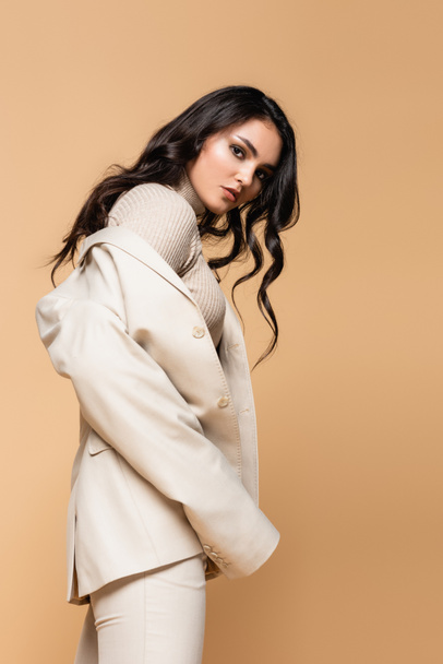 brunette model in turtleneck and blazer posing isolated on beige - Foto, immagini