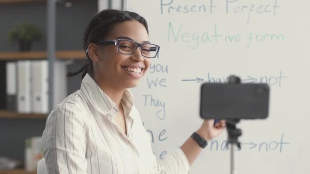 Bildungs-Videoanruf. Positive junge afrikanisch-amerikanische Lehrerin Videokonferenzen mit Schülern per Smartphone-App - Filmmaterial, Video
