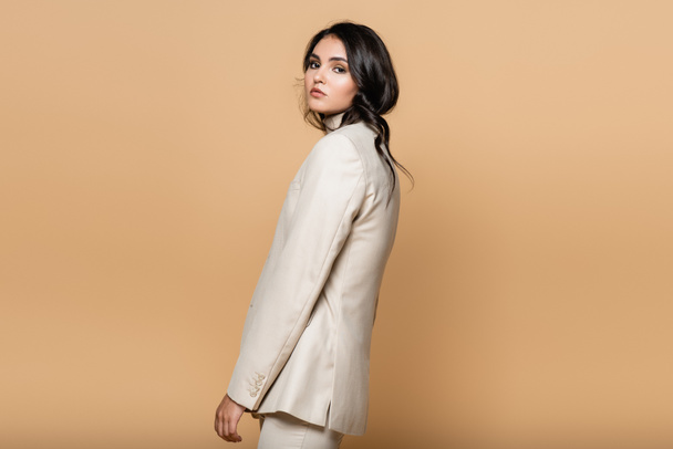 young pretty woman in turtleneck and suit looking at camera isolated on beige - Foto, Bild