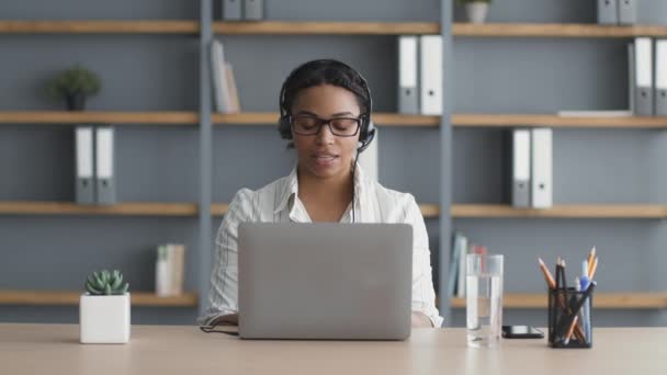Verhandlungen über Online-Geschäfte. Junge afrikanisch-amerikanische Verkäuferin im Headset im Gespräch mit dem Kunden per Videoanruf - Filmmaterial, Video