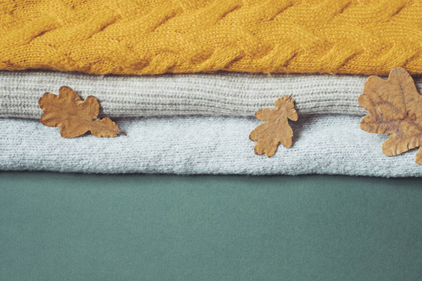 tölgyfa sárga levelek egy csomó őszi kötött pulóver hátterén. Ruházati újrahasznosítási koncepció. Kiváló minőségű fénykép - Fotó, kép