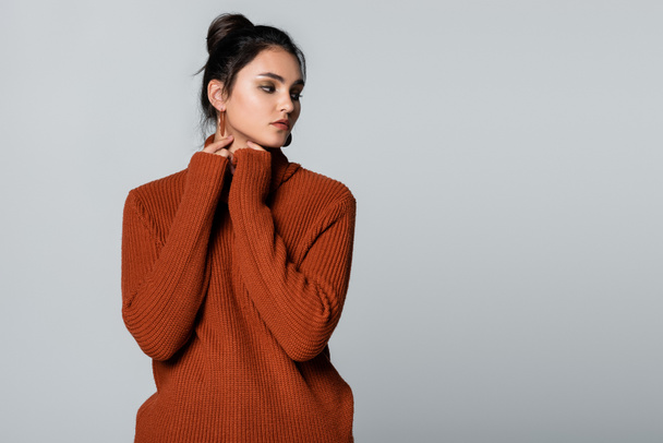 young model in knitted sweater looking away isolated on grey  - Zdjęcie, obraz