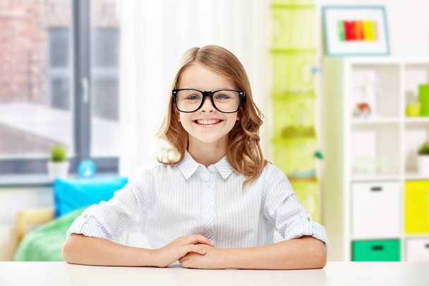 smiling student girl in glasses sitting at table - 写真・画像