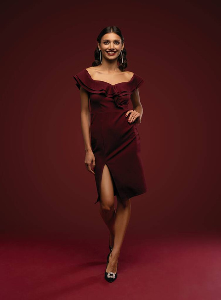 Beautiful young brunette woman with elegant hairstyle. Woman with evening make-up in red dress and high-heeled shoes - Foto, imagen