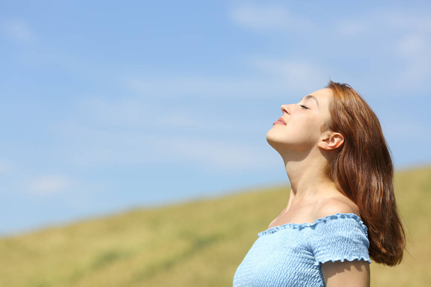 Profile portrait of a happy woman breathing fresh air in a wheat field - Fotografie, Obrázek