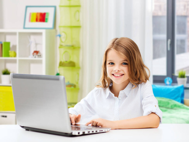 smiling student girl with laptop computer at home - Fotó, kép