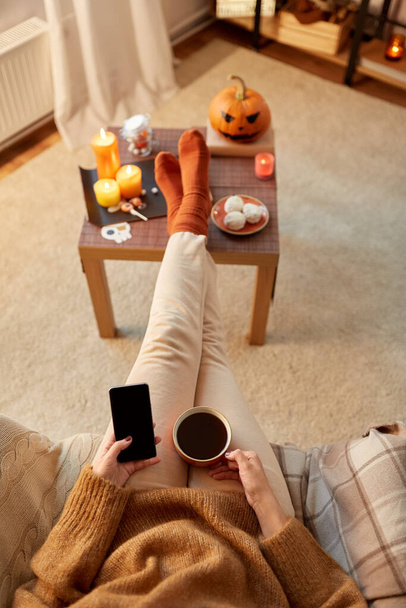 woman using smartphone at home on halloween - Zdjęcie, obraz