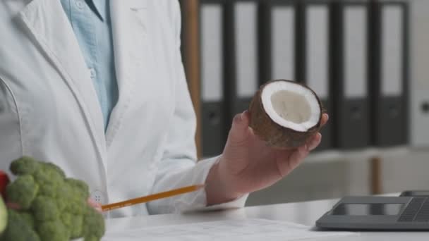 Lekarz dietetyk pokazując kokosa jako substytut mleka krowiego, rozmawiając z pacjentem z nietolerancją laktozy, śledząc strzał - Materiał filmowy, wideo