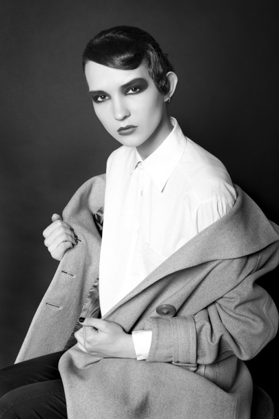 Secret retro style portrait of the young woman in a light coat against a dark background - Fotó, kép