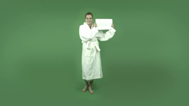 Girl in bathrobe with blank sign - Πλάνα, βίντεο