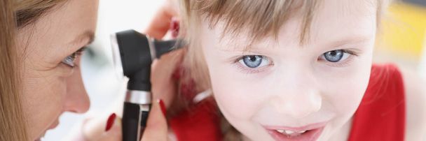 Женщина-врач проводит обследование уха маленькой девочки - Фото, изображение