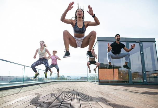 Grupo de jovens fazendo exercício ao ar livre no terraço, esporte e conceito de estilo de vida saudável. - Foto, Imagem