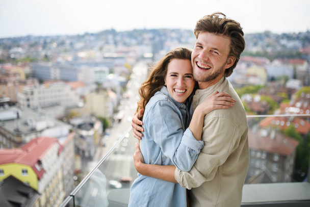 Happy young couple in love looking at camera outdoors on balcony at home, hugging. - Photo, Image