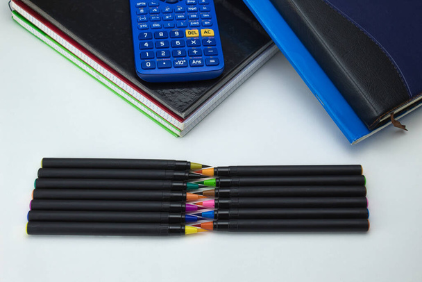 grupo de herramientas escolares con cuadernos, marcadores, bolígrafos, clips, calculadora y regla listo para volver a la escuela sobre fondo blanco - Foto, Imagen