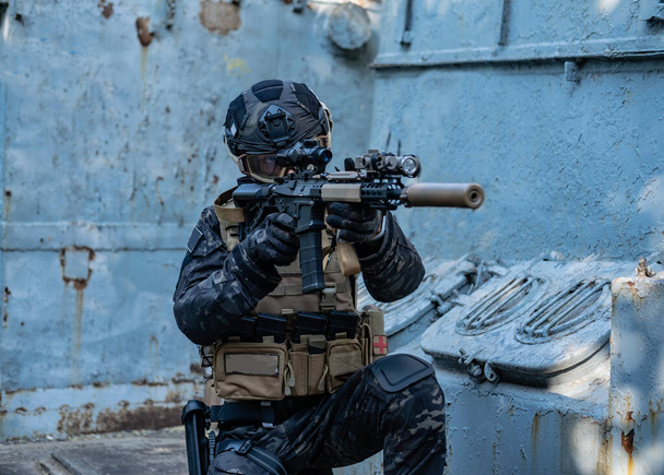 modern soldier in black multicam uniform with rifle, urban background  - Zdjęcie, obraz