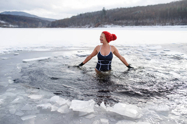 Front view of active senior woman in swimsuit outdoors in winter, cold therapy concept. - Foto, afbeelding