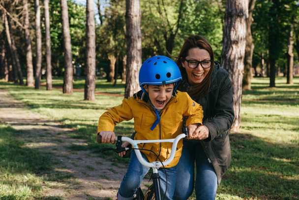 Mother teaching her son to ride a bike - Zdjęcie, obraz