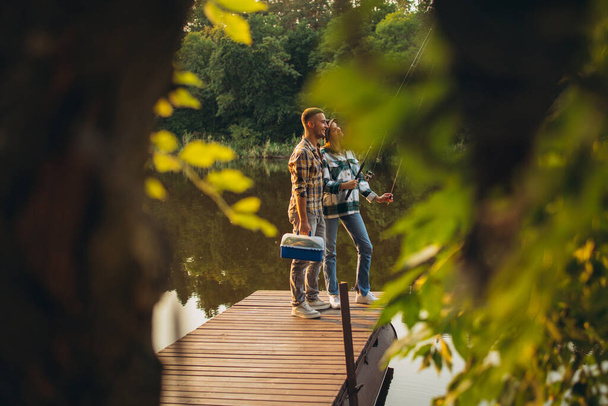 Retrato de jovem casal standinf no cais do rio e pesca. Hora de verão por do sol - Foto, Imagem