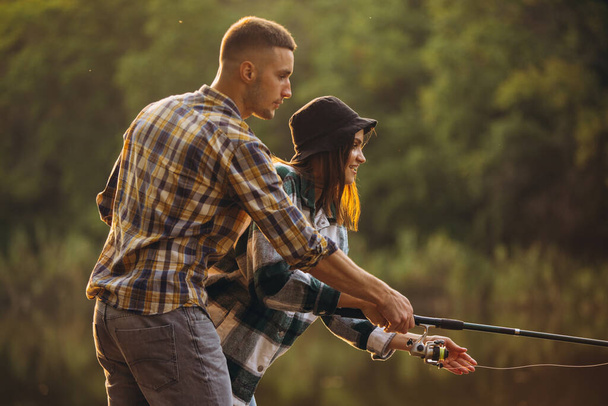 Retrato de pareja joven pescando en el cálido día de verano en el campo al atardecer - Foto, imagen