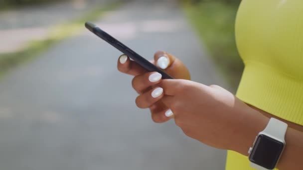 Comunicación moderna. Joven irreconocible afroamericana mujer web surf en el teléfono inteligente, charlando en línea al aire libre - Metraje, vídeo