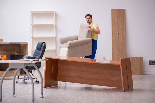 Joven carpintero masculino reparando sillón en la oficina - Foto, Imagen