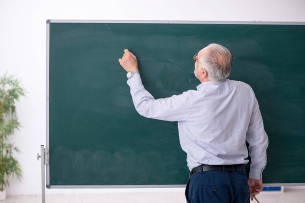 Old male teacher in front of green board - Φωτογραφία, εικόνα