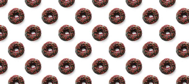 Zwarte donuts met rood glazuur op witte achtergrond naadloze patroon bovenaanzicht. Eten dessert plat plat lay van heerlijke zoete hapjes chocolade donuts banner - Foto, afbeelding