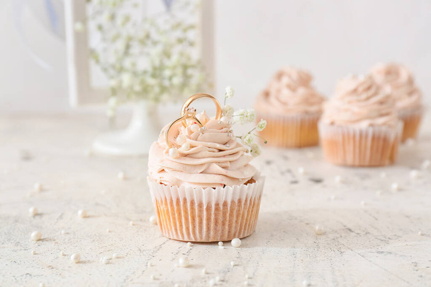 Tasty cupcake and wedding rings on table - Photo, image
