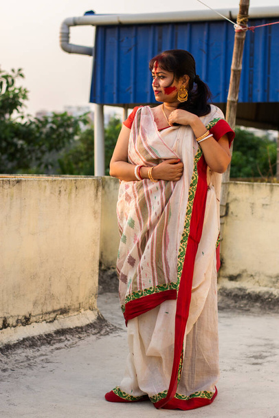 Gyönyörű indiai női modell a hagyományos bengáli száriban, amely vidáman néz ki, enyhén mosolygós arccal, sárga háttérrel, másolási hellyel a szöveg számára. Boldog hangulat koncepció - Fotó, kép
