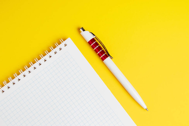 Notebook and pen on a yellow background. - Foto, Imagen