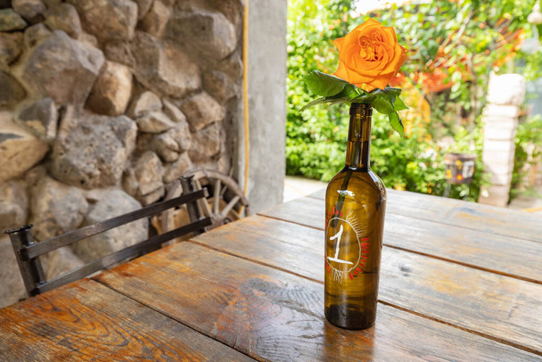 Número de la mesa en el restaurante en forma de botella de vino con una flor de rosa - Foto, imagen