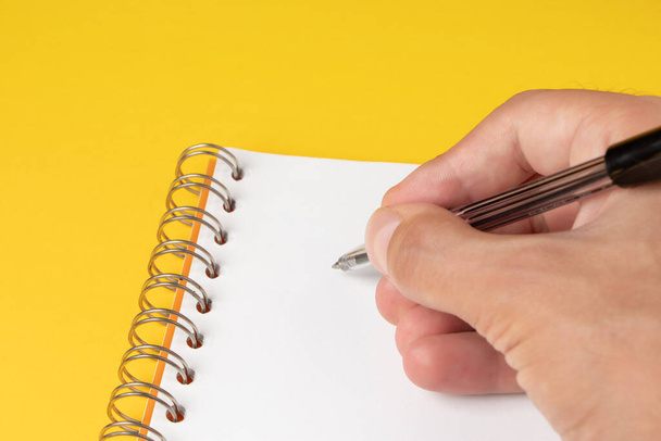 Uomini mano con penna su carta isolata su sfondo giallo. - Foto, immagini