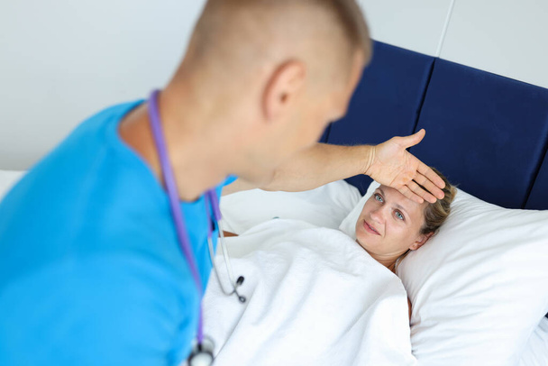 Hombre médico está proporcionando asistencia médica a paciente mujer en cama acostada - Foto, Imagen