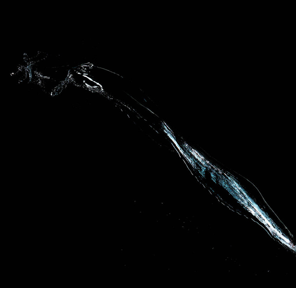 jet of transparent water with small drops and splashes on a black background - Photo, Image