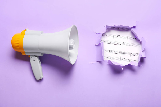 Modern megaphone and music notes visible through torn color paper - Photo, Image