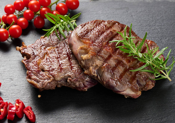 Két sült borda marhahús egy fekete palatáblán, ritka fokú készség. Bájos steak, közelről - Fotó, kép