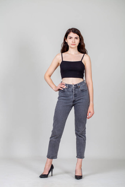Full body portrait of a young beautiful brunette model in gray jeans - Foto, immagini