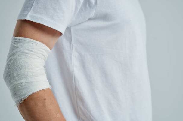 male patient in a white T-shirt with a bandaged hand isolated background - Zdjęcie, obraz