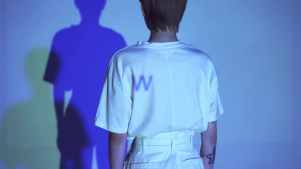 Καλλιεργημένη άποψη της γυναίκας γράμματα σε t-shirt της νεαρής γυναίκας σε μπλε φόντο  - Πλάνα, βίντεο
