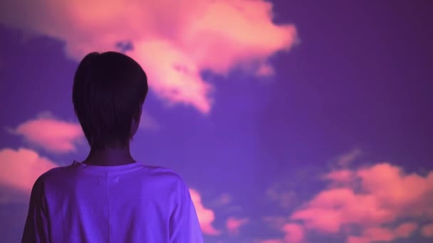 Πίσω όψη της γυναίκας που στέκεται σε μπλε φόντο με σύννεφα  - Πλάνα, βίντεο