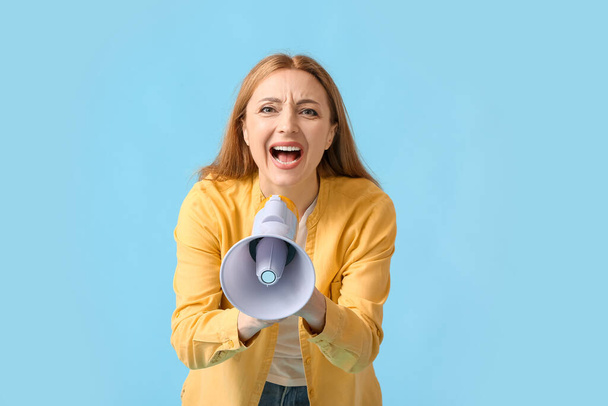 Mujer madura gritando en megáfono sobre fondo de color - Foto, Imagen