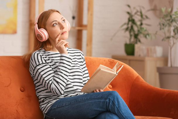Mature woman with headphones reading book at home - Foto, imagen