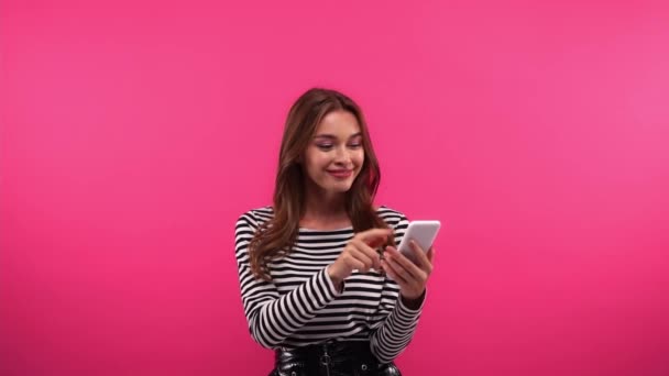 hidastettuna onnellinen nainen käyttää älypuhelinta eristetty vaaleanpunainen - Materiaali, video